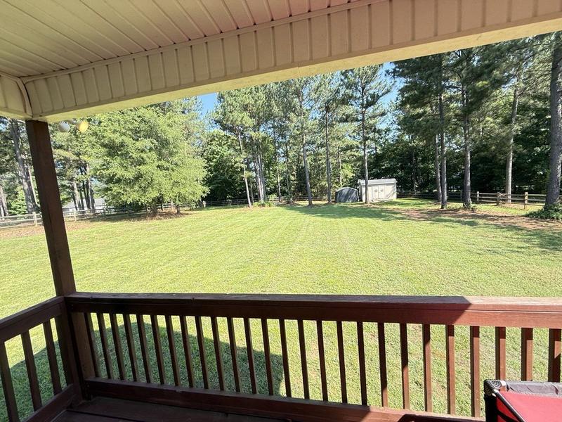 Large fenced backyard with fresh stripes, seen from a covered porch