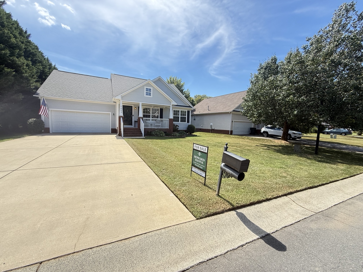 Neatly maintained front lawn and driveway at a home with a for-sale sign
